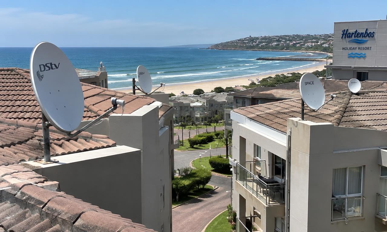Several satellite dishes on rooftops of a Hartenbos holiday complex