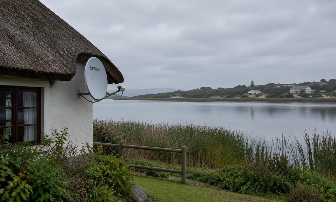 DSTV dish on a thatched cottage beside the lake in Sedgefield